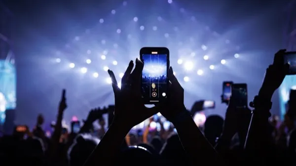 A crowd at a concert with phones raised above their heads.