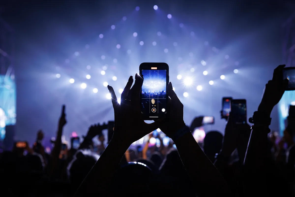 A crowd at a concert with phones raised above their heads.