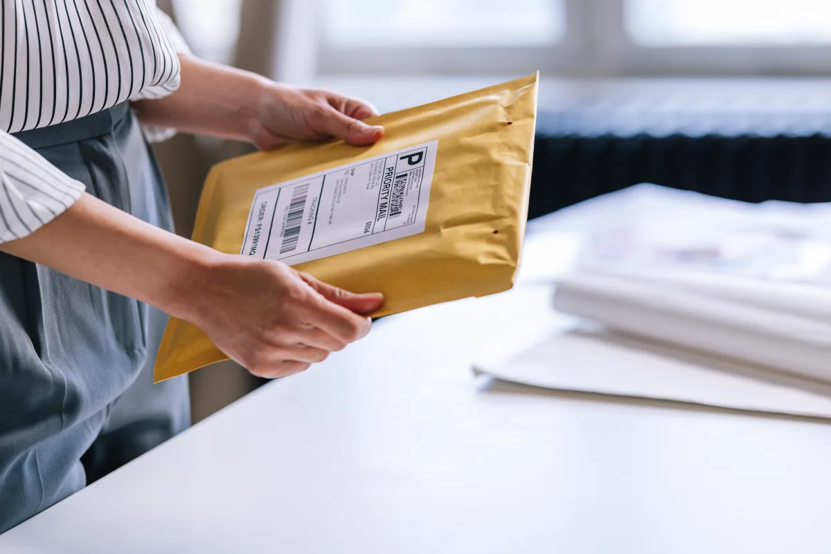 Hands taping up a cardboard box with a printed label, ready for shipping.